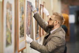 un homme qui accroche délicatement une oeuvre d'art