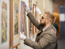 un homme qui accroche délicatement une oeuvre d'art